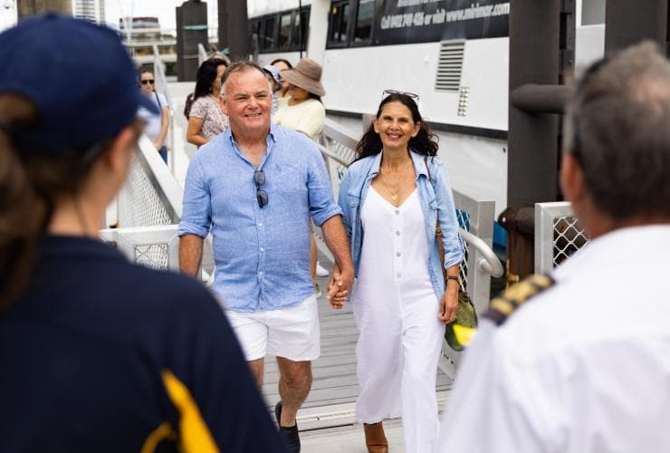 Ein Paar mittleren Alters erreicht den Pier und wird vom Personal der River City Cruises begrüßt, Brisbane/Meeanjin, Queensland © Tourism Australia