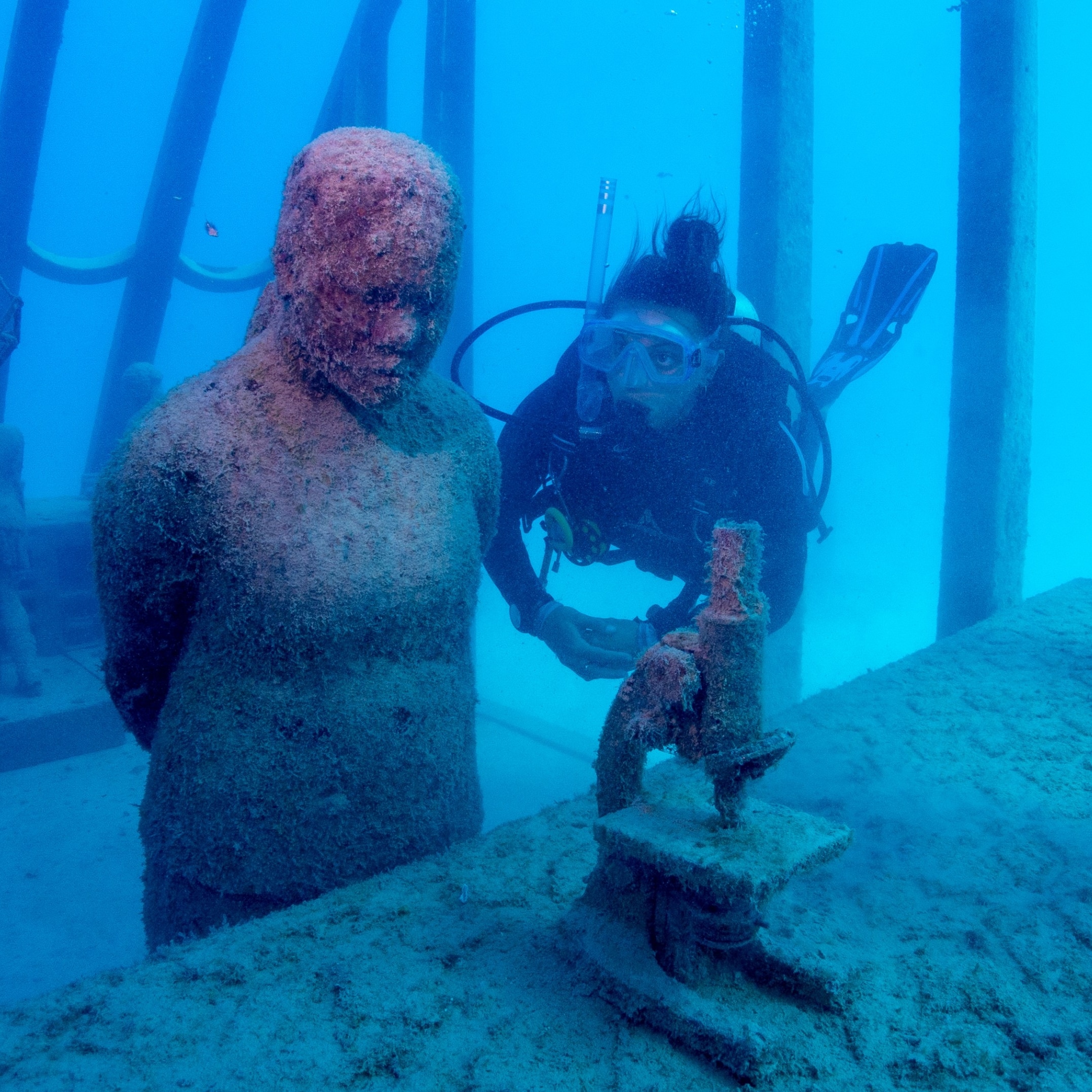 Taucher schwimmt neben einer Statue im Coral Greenhouse des Museum of Underwater Art © Gemma Molinaro Photographer