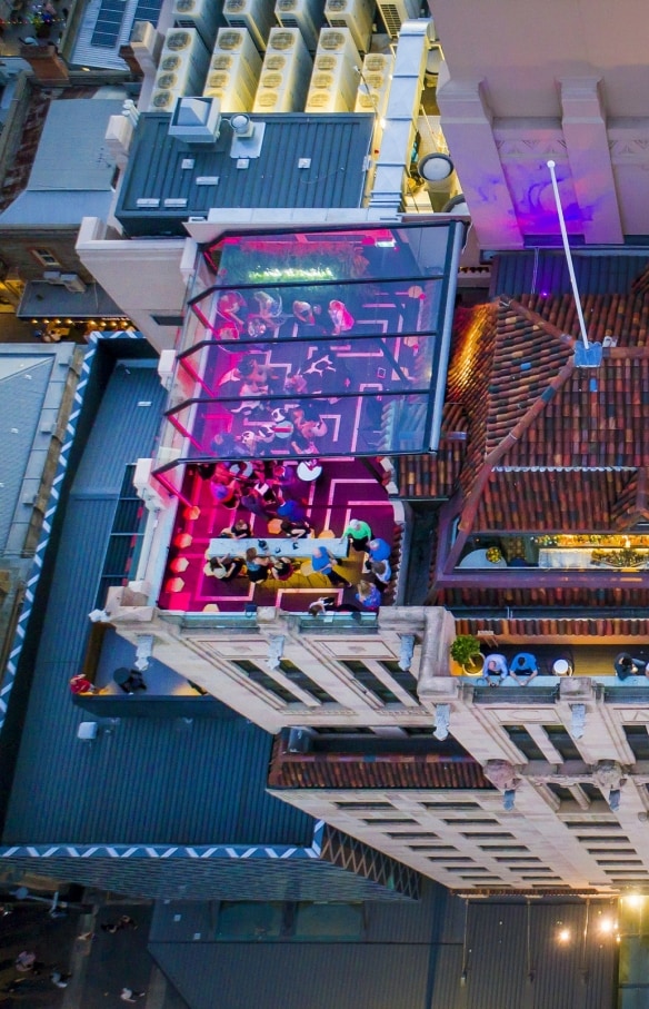 Aerial view over Hennessy Rooftop Bar lit up with pink lights and brimming with people enjoying drinks above the Mayfair Hotel, Adelaide, South Australia © Mayfair Hotel