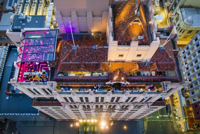 Aerial view over Hennessy Rooftop Bar lit up with pink lights and brimming with people enjoying drinks above the Mayfair Hotel, Adelaide, South Australia © Mayfair Hotel