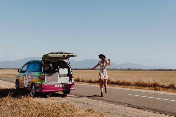 Girl standing next to JUCY campervan on the side of the road by Great Ocean Road, VIC © Jucy