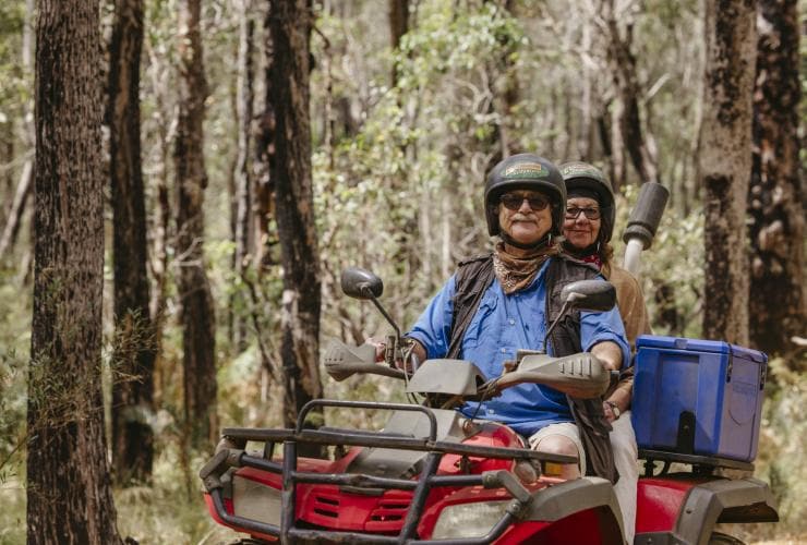Pasangan lanjut usia mengendarai motor ATV melintasi semak-semak bersama Eco Adventures Margaret River, Western Australia © Tourism Australia