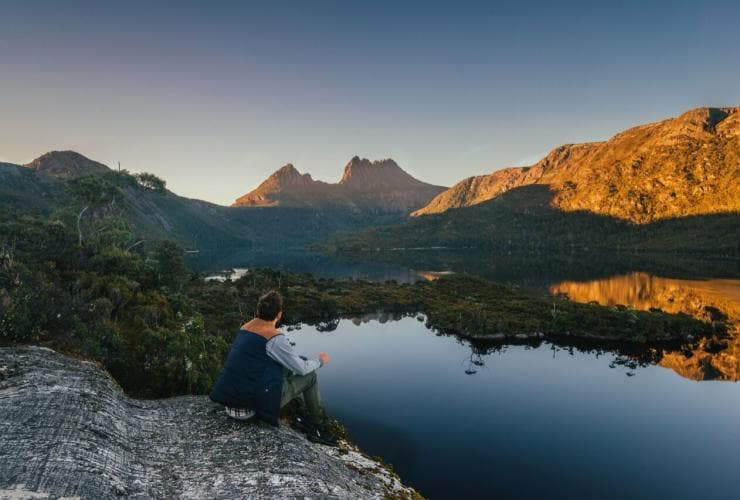 Pria menatap matahari terbenam di Cradle Mountain di sepanjang Cradle Mountain Huts Walk © Tourism Tasmania