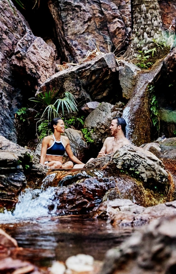 Pasangan sedang bersantai di antara mata air alami dan hijaunya pepohonan Zebedee Springs, El Questro Wilderness Park, Western Australia © Tourism Western Australia