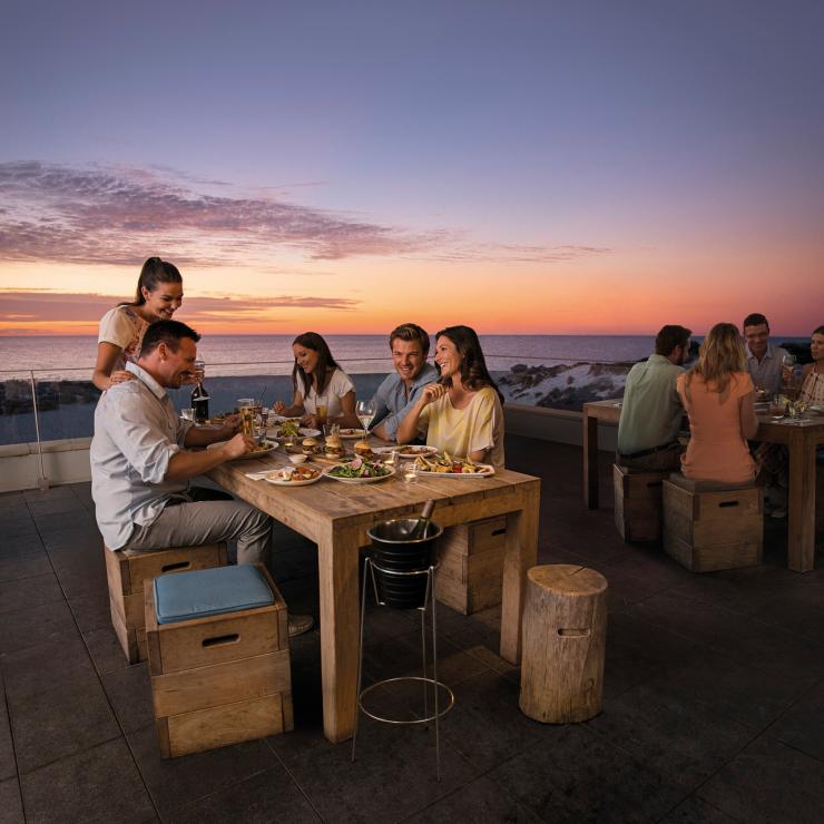 Gruppo di amici che cenano al Bib and Tucker al tramonto © Tourism Australia