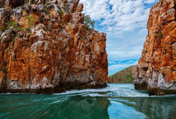 Veduta da una barca che supera le rocce rosse delle Horizontal Falls nella Kimberley Region © Lauren Bath