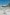 Persone sdraiate sulla sabbia bianca sotto ombrelloni colorati e altre persone che nuotano tra le placide onde e nelle acque cristalline di Greenmount Beach a Coolangatta, Queensland © Tourism and Events Queensland