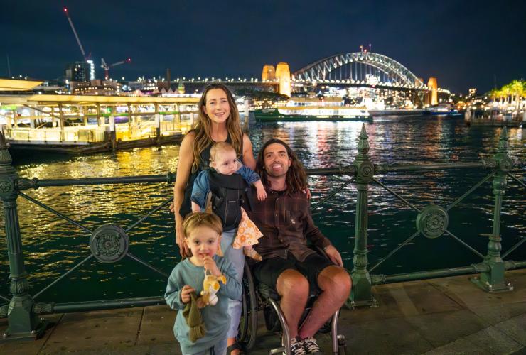 ニュー・サウス・ウェールズ州、シドニー、サーキュラー・キーで車椅子に乗る男性とその家族 © Tourism Australia