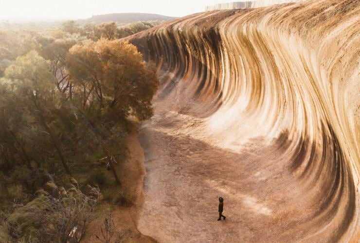 ハイデンにあるウェーブ・ロックの真下に立つ人物 © Australia's Golden Outback
