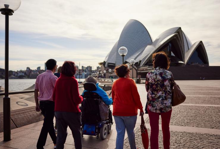 휠체어를 탄 남성이 가족과 함께 시드니 오페라 하우스를 향해 이동하고 있는 모습, 오스트레일리아 인 스타일, 시드니, 뉴사우스웨일스 © 뉴사우스웨일스주 관광청