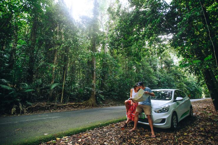 Ein Paar liest eine Landkarte auf der Motorhaube seines Mietwagens in der Nähe von Cairns © Jucy Rentals
