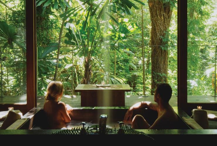 Ein Pärchen nimmt in seiner Unterkunft in der Silky Oaks Lodge gemeinsam ein Bad mit Ausblick aus dem Fenster auf den Daintree Rainforest in Port Douglas, Queensland © Silky Oaks Lodge