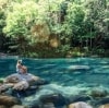 Woman sits on rock beside rockpool at Mossman Gorge © Tourism and Events Queensland