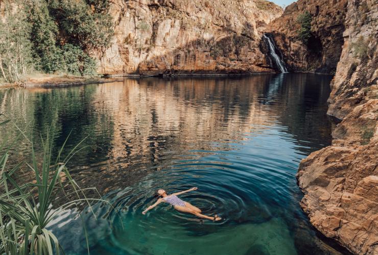 A person floating on their back in turquoise waters surrounded by rocky walls in Barramundi Gorge (Maguk), Kakadu National Park, Northern Territory © Tourism NT/Adriana Alvarado