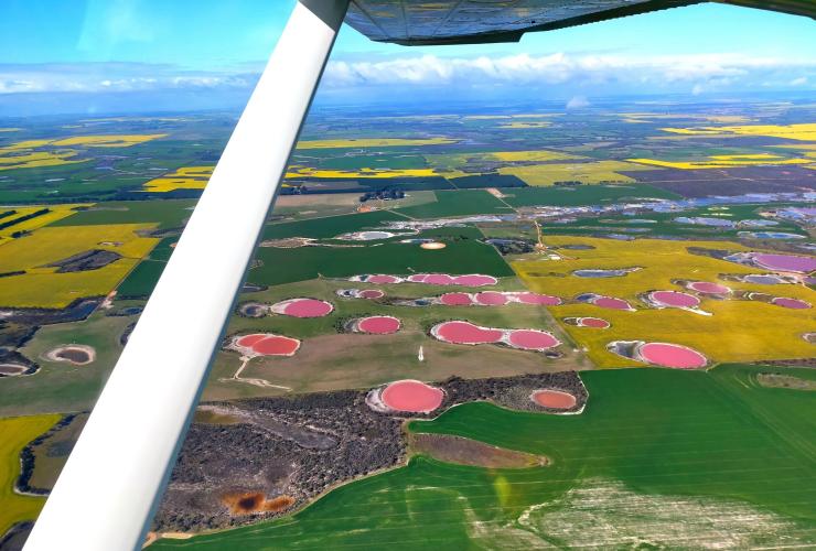 Pemandangan udara dari penerbangan wisata melintasi danau merah muda dan danau berwarna pelangi yang tersebar di seluruh lahan pertanian, Golden Outback, Western Australia © Golden Outback