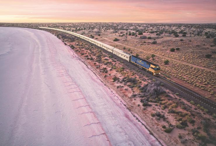 Vista dell'Indian Pacific Train che viaggia lungo il lago rosa Lake Hart al tramonto nell'outback del South Australia © Andrew Gregory
