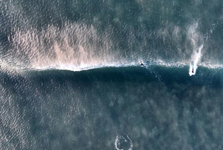 ビクトリア州、グレート・オーシャン・ロード、ベルズ・ビーチで波に乗るサーファーたちの空撮 © Tourism Australia