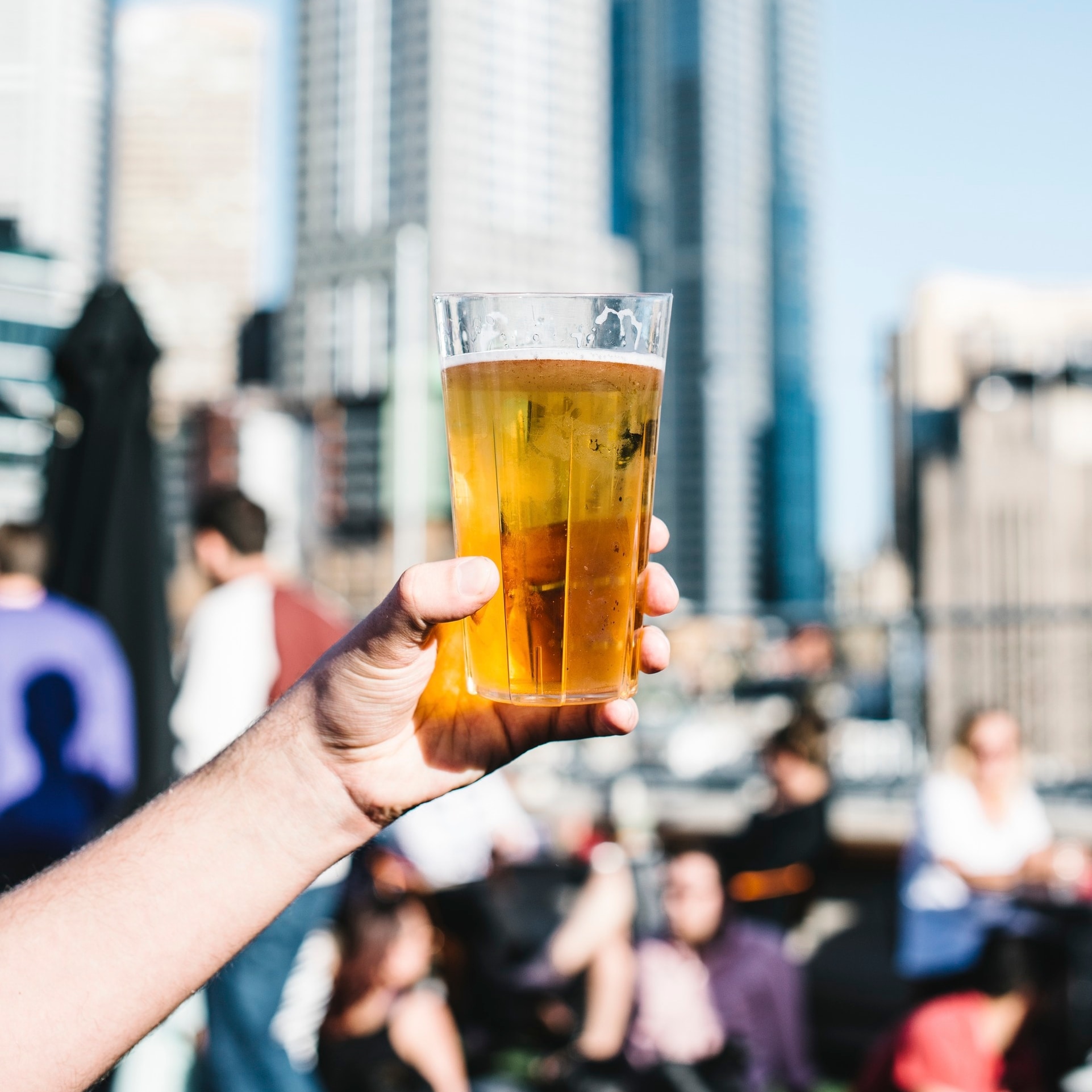 Eine Hand hält ein Pint Bier in einer Rooftop-Bar in Melbourne © Tourism Australia