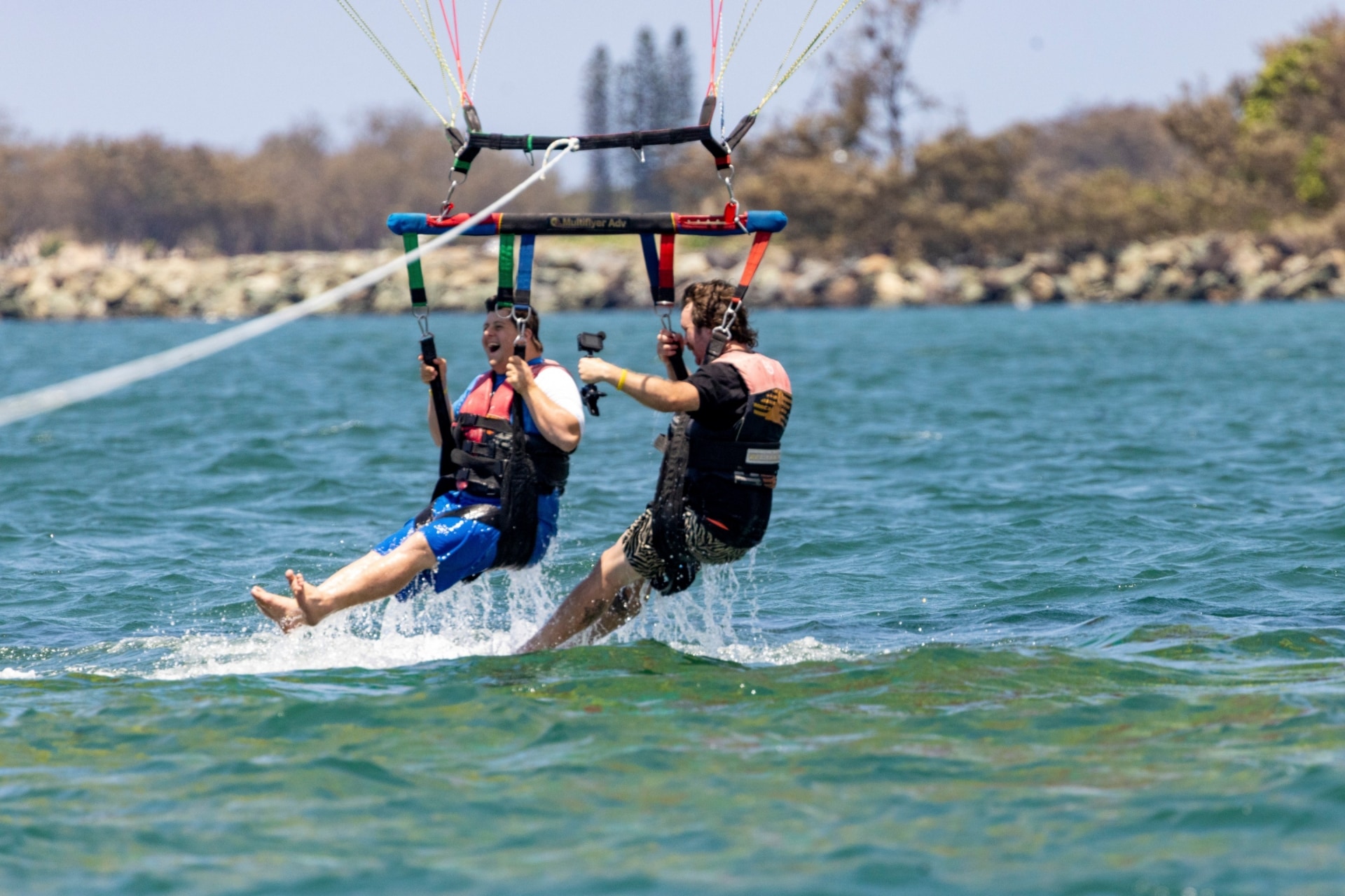 Man with neurdivergence parasailing with  another man at Gold Coast Water Sports, Gold Coast, Queensland © Tourism and Events Queensland