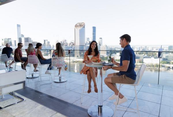 People sitting at high tables on a rooftop bar overlooking a city, Terrace Bar, Brisbane, Queensland © Brisbane Economic Development Agency