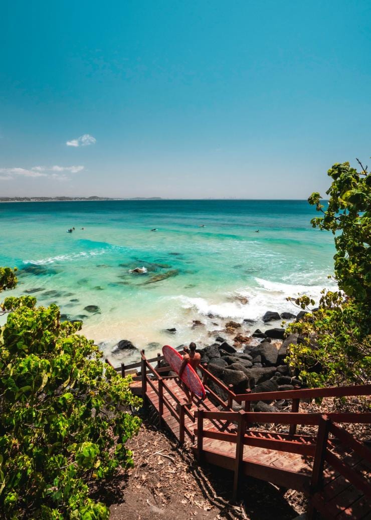 Surfer walking toward Rainbow Bay on the Gold Coast © Tourism and Events Queensland