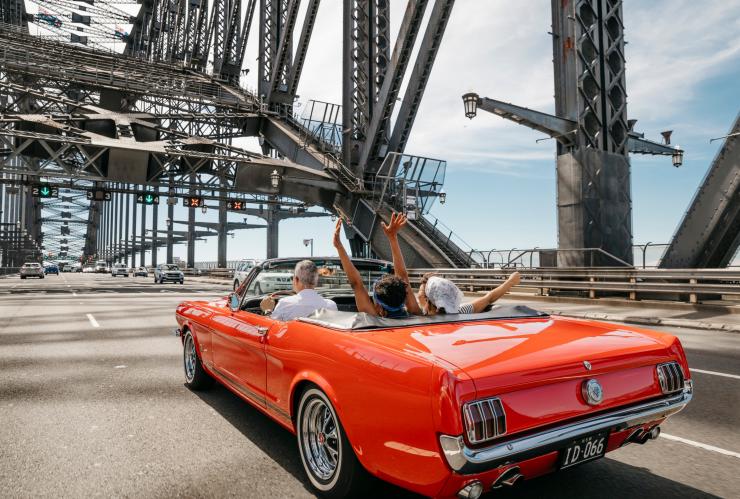 Friends being chauffeured over the Sydney Harbour Bridge with Sydney Mustang Wedding Cars, Sydney, NSW © Destination NSW