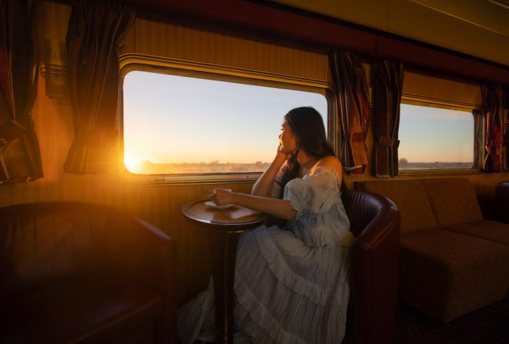 Woman enjoying a hot drink onboard the Ghan © Tourism NT/Daniel Tran