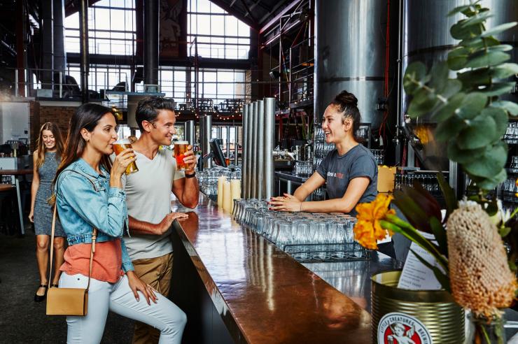 A man and woman sipping beer at the bar while chatting to a smiling bartender at Little Creatures Brewery, Fremantle, Western Australia © Illustrations Photography A man and woman sipping beer at the bar while chatting to a smiling bartender at Little Creatures Brewery, Fremantle, Western Australia © Illustrations Photography