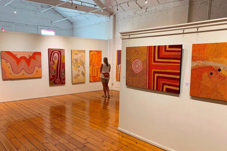 A woman admiring vibrant orange dot paintings and Aboriginal art at Japingka Gallery, Fremantle, Western Australia © Japingka Gallery A woman admiring vibrant orange dot paintings and Aboriginal art at Japingka Gallery, Fremantle, Western Australia © Japingka Gallery