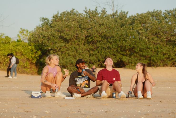 A group of four friends sitting on a sandy beach with bushland behind them during a working holiday in the Top End, Northern Territory © Tourism NT/Kane Chenoweth