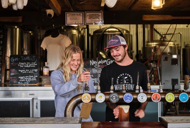 Two bartenders smiling while pouring drinks from a row of taps at Whalebone Brewing Co, Exmouth, Western Australia © Tourism Western Australia