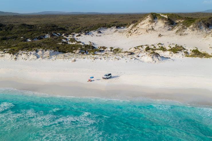 Couple sunbathing on the beach next to 4WD at Cape Le Grand National Park © Australia's Golden Outback