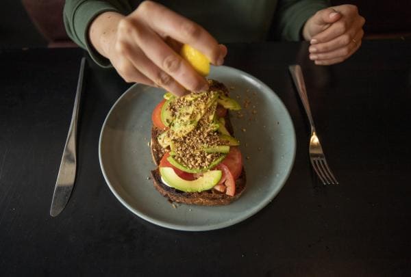 A person squeezing lemon onto avocado toast, Eightysix, Braddon, Canberra, Australian Capital Territory © Tourism Australia