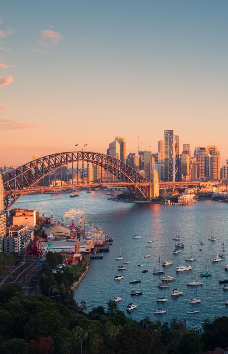 Aerial view over a tranquil blue harbour sprinkled with boats with an arched bridge leading to a city skyline in Sydney Harbour, Sydney, New South Wales ©Tourism Australia