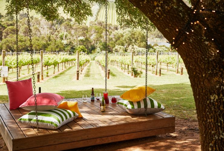 Pillows and drinks on a large wooden swing at Tucks Wine © Griffin Simm