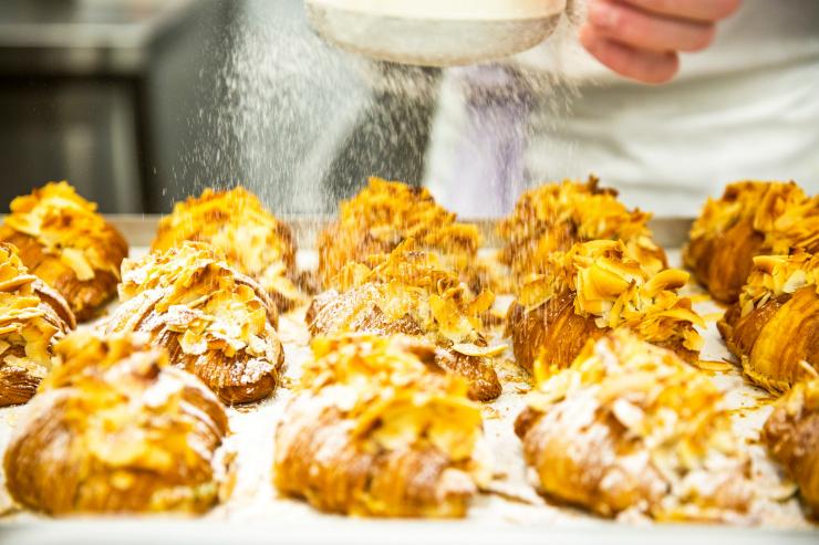 A person dusting a tray full of golden, flaky croissants with icing sugar at Lune Croissanterie, Melbourne, Victoria © Visit Victoria A person dusting a tray full of golden, flaky croissants with icing sugar at Lune Croissanterie, Melbourne, Victoria © Visit Victoria