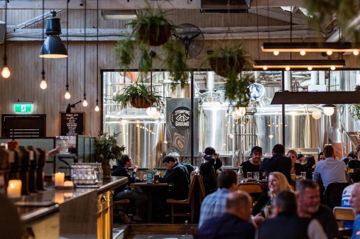 A venue filled with smiling people sitting at tables with plants hanging from the roof at Stomping Ground Brewery Co., Collingwood, Victoria © Stomping Ground Brewery Co. A venue filled with smiling people sitting at tables with plants hanging from the roof at Stomping Ground Brewery Co., Collingwood, Victoria © Stomping Ground Brewery Co.