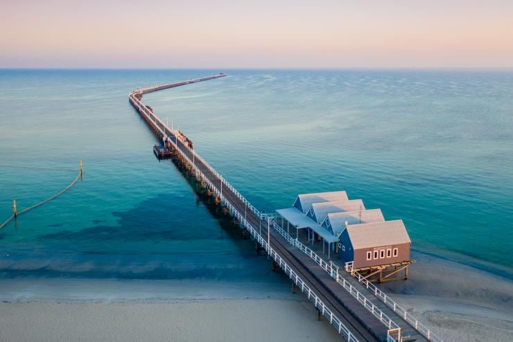 Aerial view of Busselton Jetty stretching out into the clear blue ocean with a purple sunset filling the sky in Busselton, Western Australia © Tourism Western