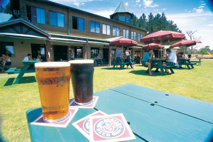 A close up of beers on a table with people sitting in the sunshine enjoying drinks in the background at Bootleg Brewery, Margaret River, Western Australia © Tourism Western Australia
