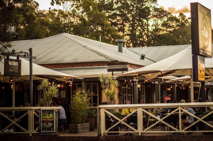 Exterior of Settlers Tavern at sunset with people sitting around outdoor tables enjoying food and drinks in  Margaret River, Western Australia © Settlers Tavern