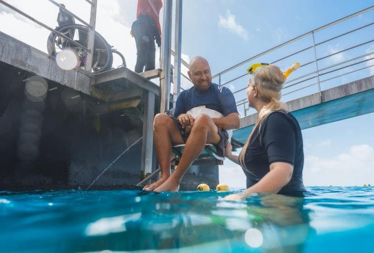 Wheelchair user being lowered into the ocean on a lift with Quicksilver Cruises, Great Barrier Reef, Queensland © Tourism and Events Queensland