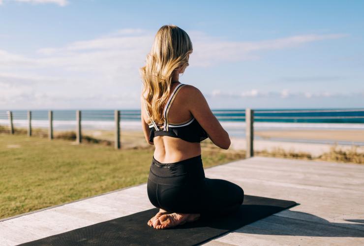 Woman doing yoga by the beach at Elements of Byron Bay © Destination NSW
