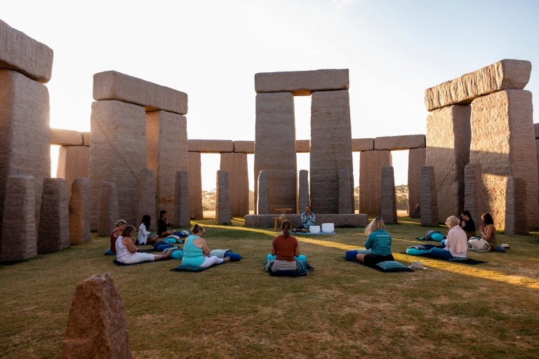 A group of women sitting in a circle on the grass, surrounded by large grey boulders in Esperance, Western Australia © Tourism Australia