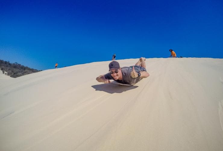 Tobogganing the sand dunes, Moreton Island Desert, Moreton Island, QLD © Tourism Australia
