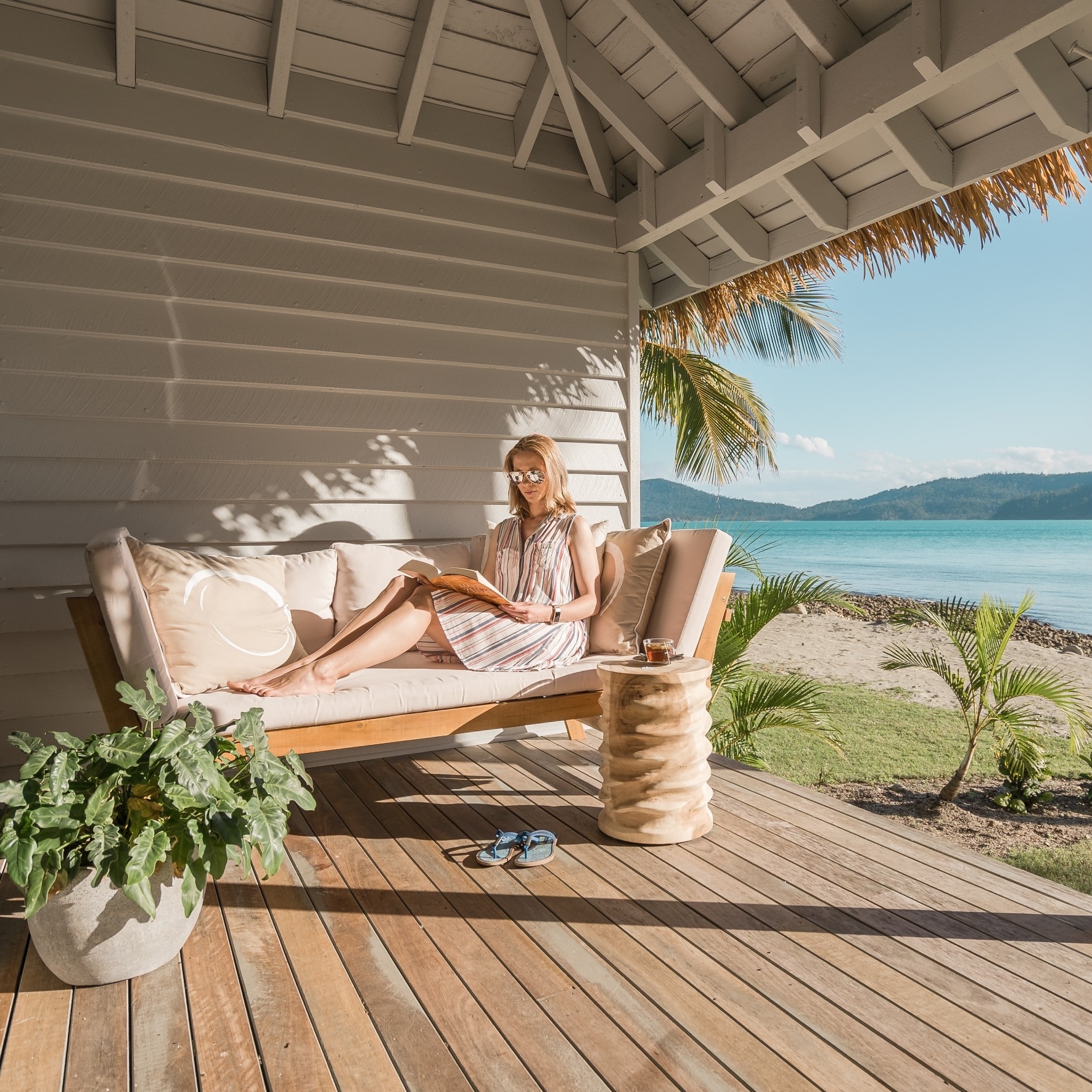 Une femme lit sur un balcon donnant sur l'océan à Elysian Retreat © Elysian Retreat/Nathan White