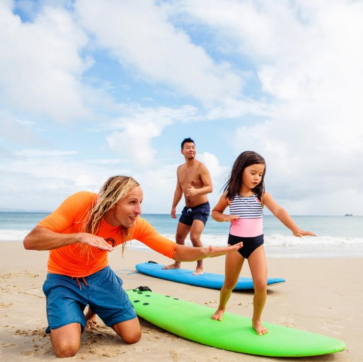 Famille apprenant à surfer sur Clarkes Beach, Byron Bay. © Destination NSW