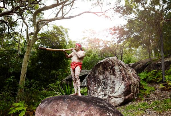 Homme jouant du didgeridoo sur le rocher, Pretty Beach House, Bouddi National Park, NSW © Pretty Beach House