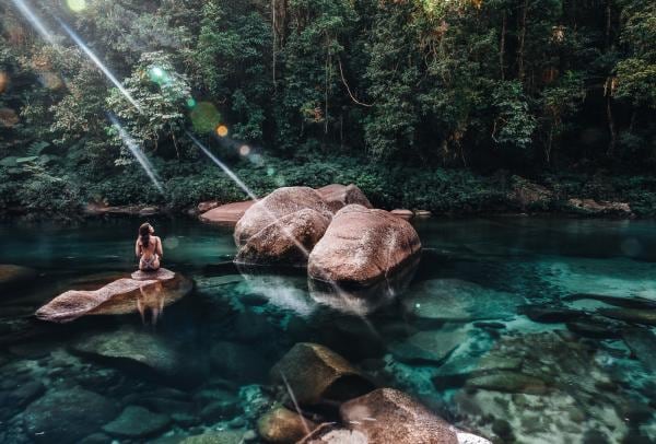 Jeune femme assise sur un rocher dans des eaux bleu-vert © Katie Purling/Tourism and Events Queensland