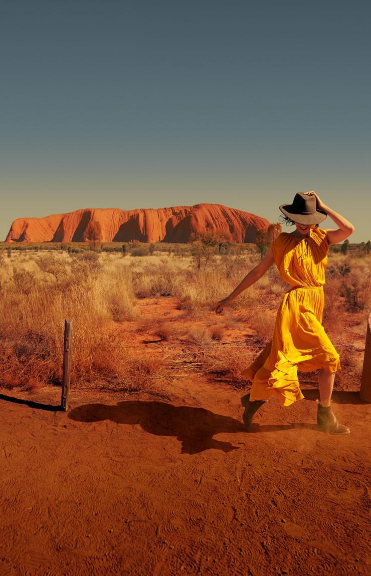 Femme qui marche au pied d'Uluru dans l'Uluru-Kata Tjuta National Park, dans le Territoire du Nord © Tourism Australia