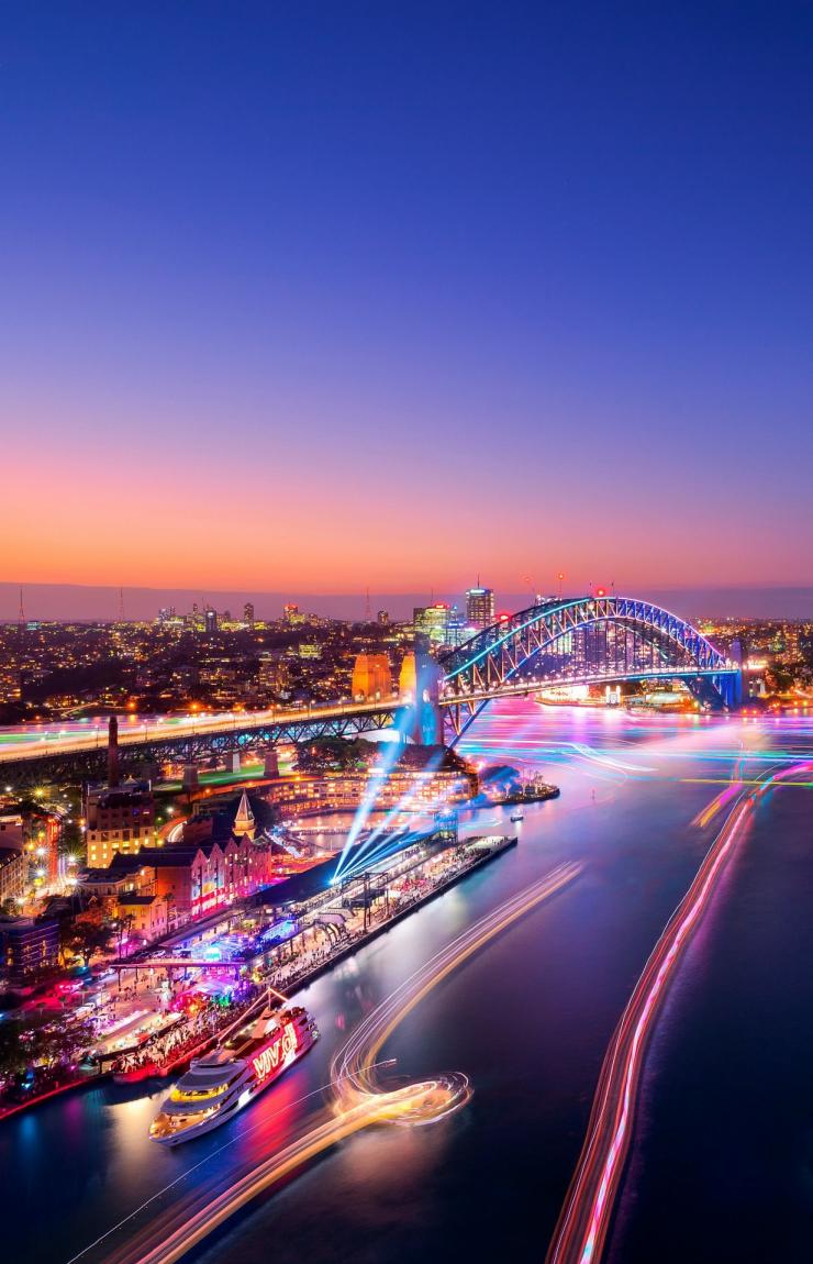 Pemandangan dari udara di atas kota pelabuhan diterangi lampu warna-warni dalam Vivid Sydney, Sydney, New South Wales © Destination NSW